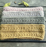 stack of folded star stitch crochet headbands in various neutral and pastel colors on a wooden surface thumbnail