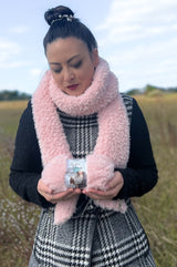 Woman in pink scarf standing in field, holding ball of yarn thumbnail