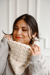 Woman wearing white cowl, hands near face thumbnail