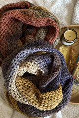 Two crochet cowls on a bed with a candle thumbnail