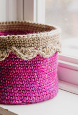 Pink basket with tan edging sits on windowsill thumbnail