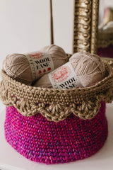 Pink basket with tan edging holding two balls of yarn thumbnail