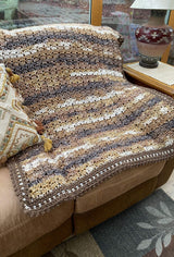 Brown & cream crochet blanket on tan armchair.  thumbnail