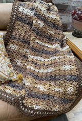 Brown & cream crochet blanket on couch, indoors.  thumbnail