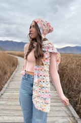 Woman wearing crochet bonnet and scarf on boardwalk outdoors.  thumbnail