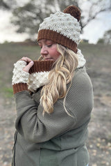Woman facing left holds crochet cowl out, while wearing matching hat & mitts.  thumbnail