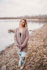Model wears tan crochet cardigan on rocky lakeshore. thumbnail