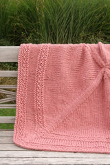 Coral pink blanket on wooden bench outdoors.  thumbnail