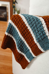 Brown, ivory, and teal striped blanket on cream couch.  thumbnail
