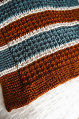 Close up on border of brown, ivory, and teal blanket.  thumbnail