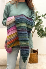 Model holds shawl with dark green-red end and pink-orange end, indoors.  thumbnail