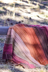 Red-purple-pink blanket pictured on wooden fence outdoors, against scrubby grass thumbnail