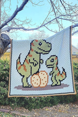 Crochet afghan with t-rex family hangs from a tree branch thumbnail