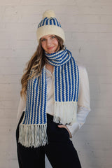 Model wears blue and white striped hat and scarf set in front of white wall thumbnail