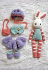 Fuzzy crochet bunny with aqua body, red & white striped arms and legs, with wardrobe next to it. Purple hat, aqua vest, purple skirt & shoes, red bag.  thumbnail