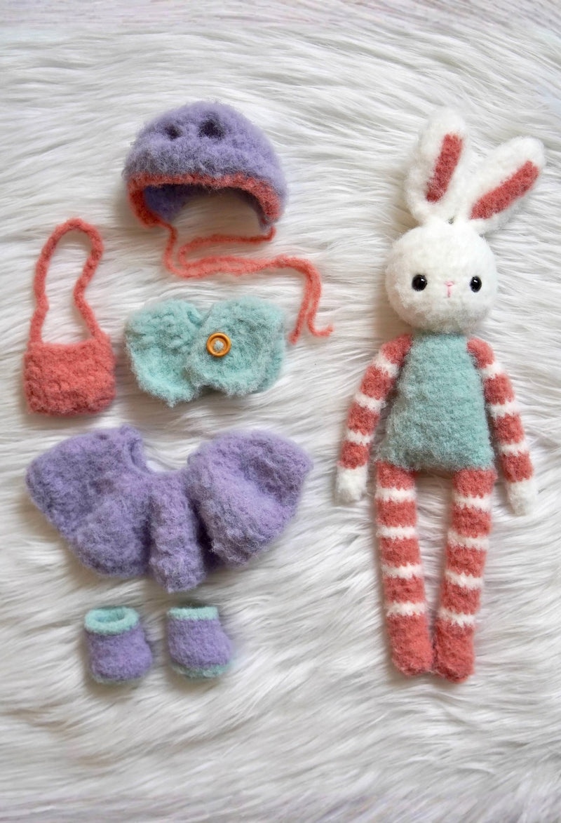 Fuzzy crochet bunny with aqua body, red & white striped arms and legs, with wardrobe next to it. Purple hat, aqua vest, purple skirt & shoes, red bag. 