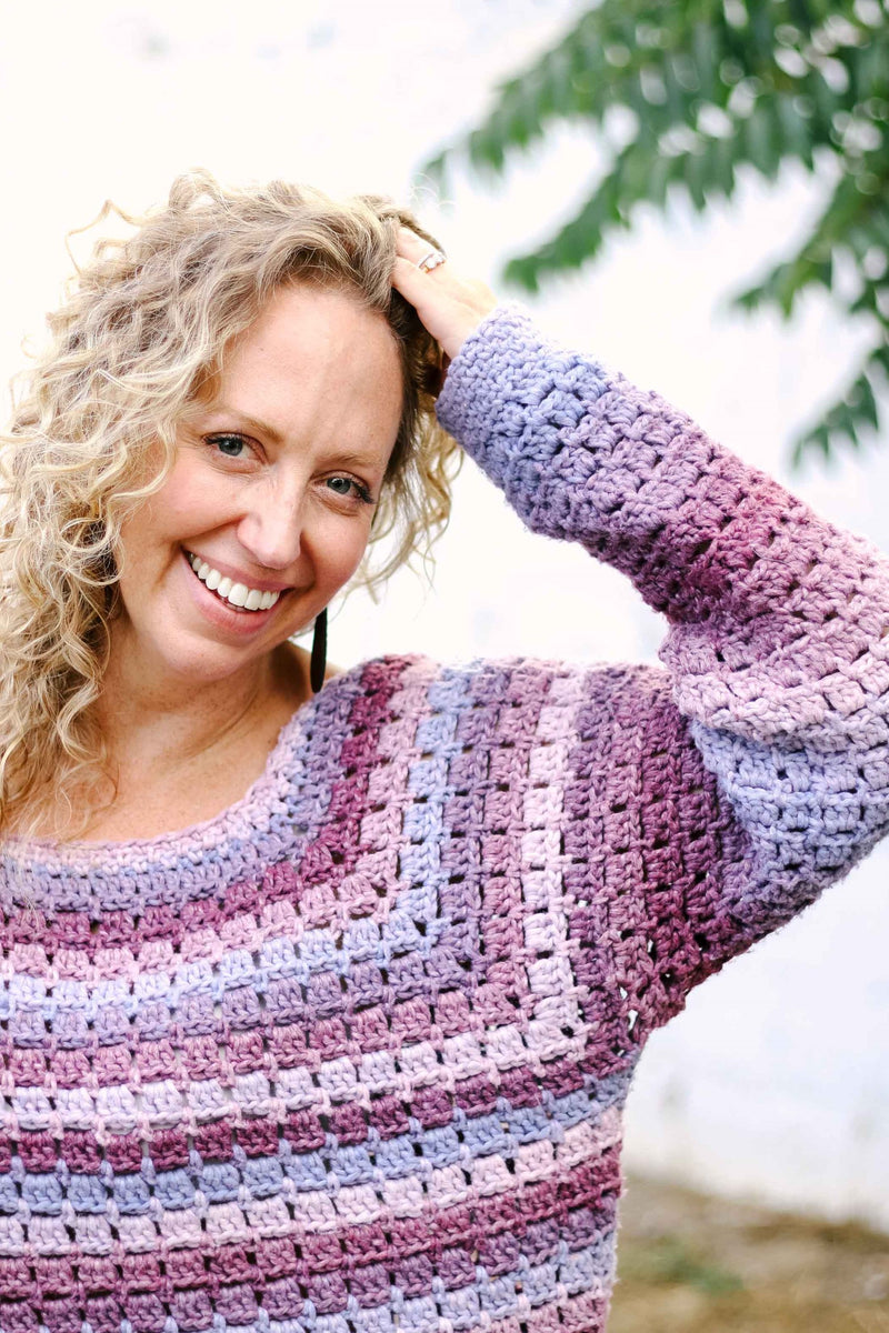 Close up of raglan shaping and sleeve of purple & pink crochet sweater. 