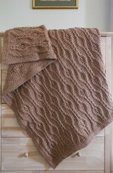 Brown crochet blanket draped over wooden dresser. thumbnail