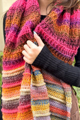 Close up of crochet shawl with blocks of pink-orange and multi-colored textured sections.  thumbnail