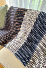 Color blocked striped blanket draped along back of cream couch.  thumbnail