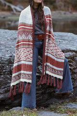 Woman wears knit wrap in cream, red, and tan while standing against a boulder.  thumbnail