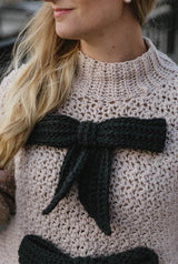 Close up on front of tan sweater with black bows.  thumbnail