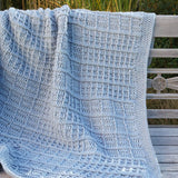 Blue grey crochet blanket laid over wooden outdoor bench.  thumbnail