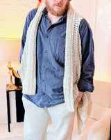Man wears pale crochet vest over denim shirt and cream pants.  thumbnail