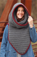 Woman wears oversized grey cowl with hood pulled up, showing red trim. Front of cowl ends in a triangular point at waist.  thumbnail
