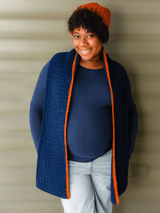 Pregnant woman wears navy crochet scarf with orange stripe on one edge, with matching orange hat.  thumbnail