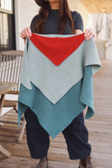 Woman holds three triangular crochet shawls toward camera. Smallest is red-orange, medium is pale blue, and largest is turquoise.  thumbnail