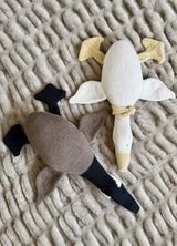 Two knit geese on a plush blanket. One goose is knit as a Canada goose in white, black and taupe. The other goose is all white with yellow bill and feet, and a yellow bandana.  thumbnail