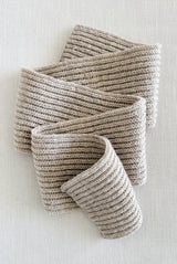 Beige ribbed scarf folded in ribbon shape on cream background.  thumbnail