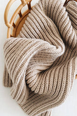 Knit throw with ribbed textured piled in wooden cane basket.  thumbnail