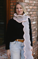 Woman wears pale grey knit scarf with cream trim, over black sweater and jeans.  thumbnail