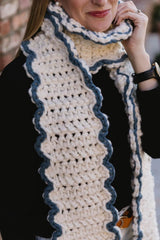 Close up of cream scarf showing crochet texture and blue trim.  thumbnail