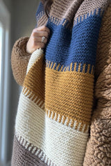 Side view close up of knit wrap worn over fuzzy sherpa coat.  thumbnail