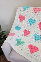 Crochet blanket with heart motif blocks, in pink, blue, and green, with white background.  thumbnail