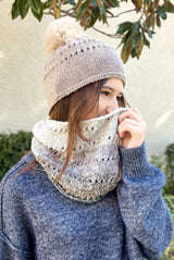 Woman in grey top wears a tan knit beanie with faux fur pompom and an ombre knit cowl.  thumbnail