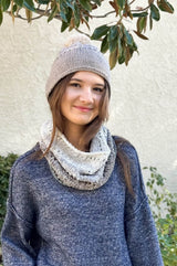 Woman faces camera wearing tan beanie and cowl that fades from cream to brown to black.  thumbnail