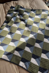 Crochet blanket laid on tan duvet, with green and navy/blue/white blocks.  thumbnail
