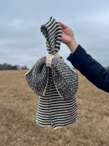 Close up of bow scarf held by hand of person off-camera.  thumbnail
