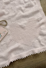 Close up of pale pink baby blanket with a heart motif knit in garter stitch on stockinette background.  thumbnail