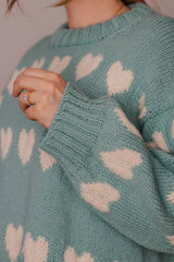 Close up of cream hearts on seafoam green sweater, showing ribbed cuffs and neckband.  thumbnail