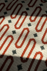 Close up of oval motifs in orange and stars in dark green on a cream background.  thumbnail