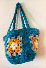 Crochet bag hangs on white wall, showing granny square front and side panels.  thumbnail