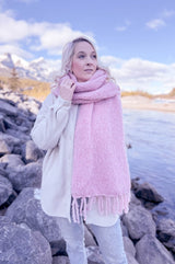 Woman wears fluffy pink scarf draped over one shoulder, showing fringe and width of scarf.  thumbnail