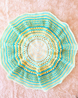 Full view of circular crochet afghan, in shades of yellow and aqua green. There are bands of plain stitches and textured rounds.  thumbnail