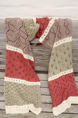Lace wrap draped over the back of a wooden bench. The wrap is worked in sections of cream, sage green, dark rose, and taupe.  thumbnail