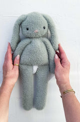 Sage green bunny toy with long floppy ears and limbs, held up against a white background.  thumbnail